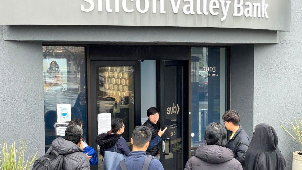 A worker (C) tells people that the Silicon Valley Bank (SVB) headquarters is closed on March 10, 2023 in Santa Clara, California.