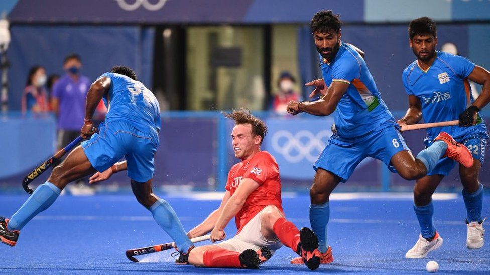 Британец Кристофер Гриффитс (2-й слева) падает между индийцем Амитом Рохидасом (слева) и Сурендером Кумаром во время мужского четвертьфинального матча Олимпийских игр 2020 года в Токио.