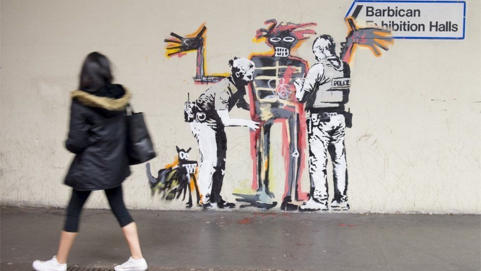 A woman passes one of two new murals painted by the artist Banksy near the Barbican Centre in London.