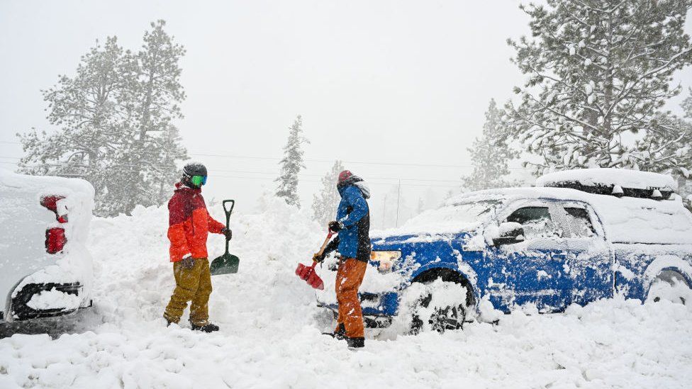 Men remove snow around their vehicles as snow blanketed Emerald Bay Road in Lake Tahoe, California