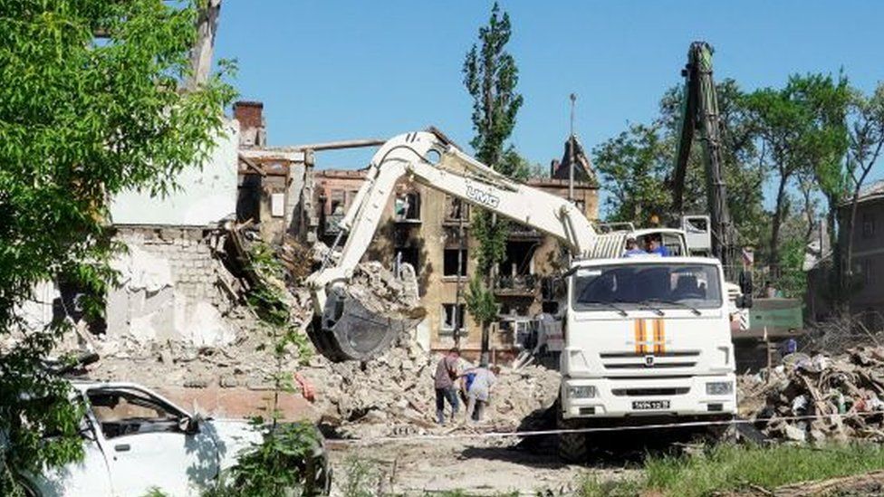 A vehicle clears rubble