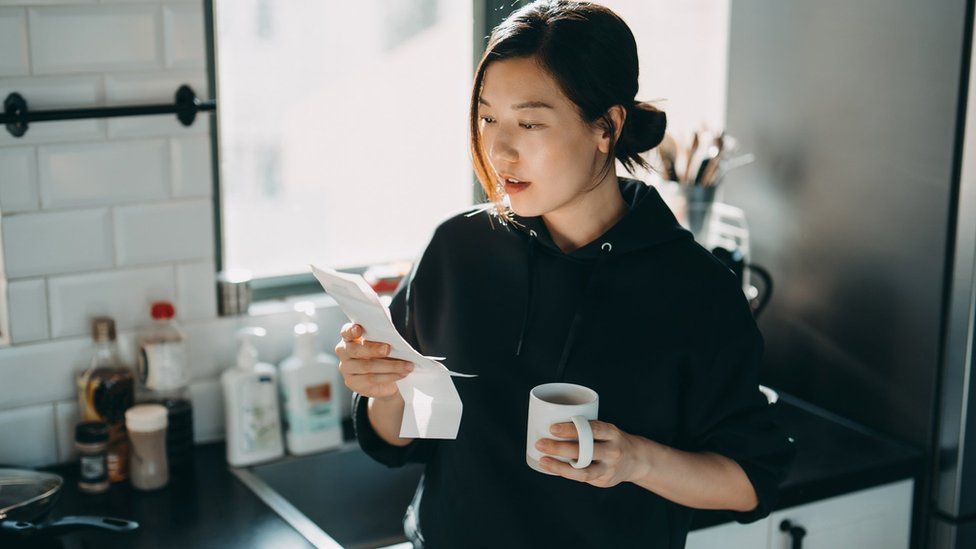 Woman looking at energy bill while having a cup of tea