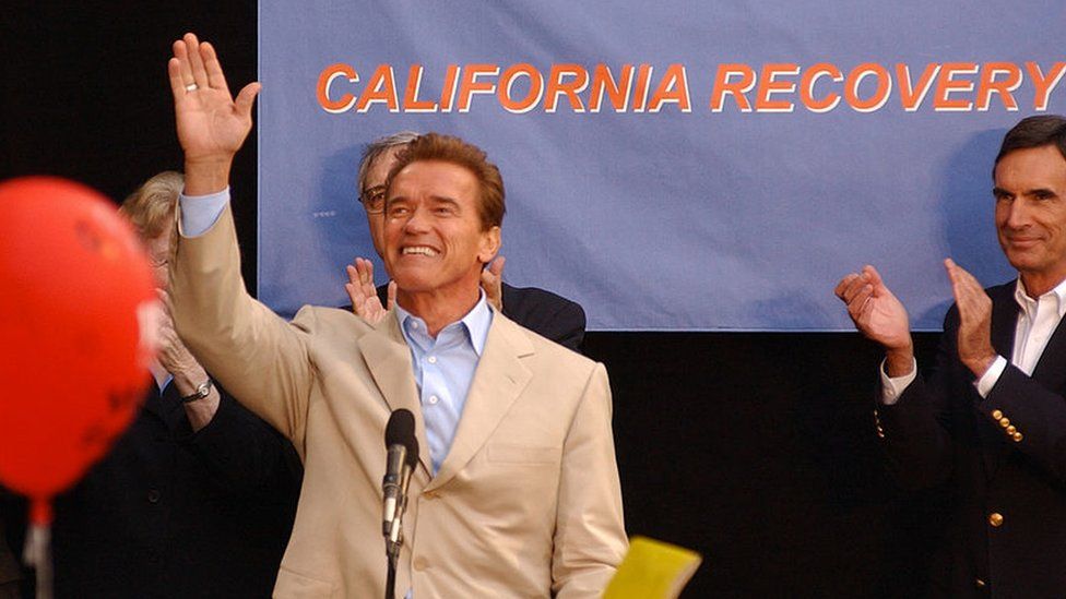 Arnold Schwarzenegger waves at a campaign rally in 2003