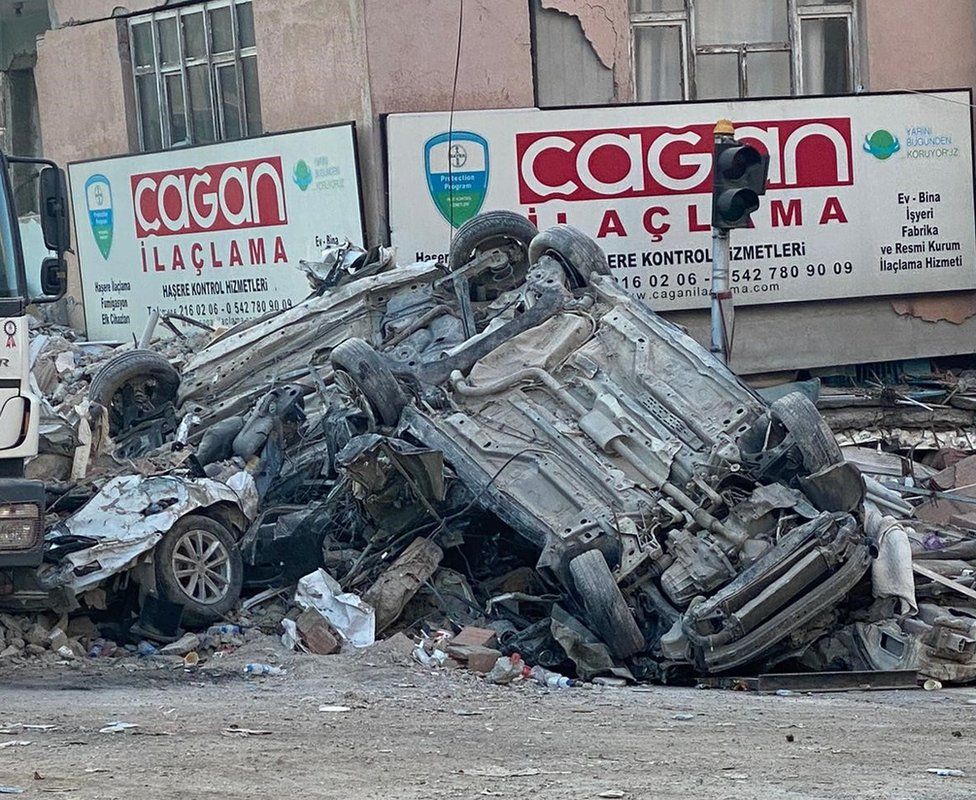 Overturned cars amid the wreckage and devastation caused by the earthquake in Adana