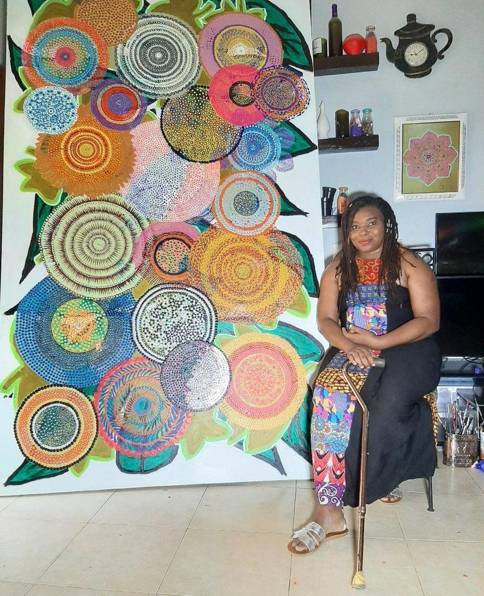 Ijeoma Ogwuegbu next to a large Dot Art painting
