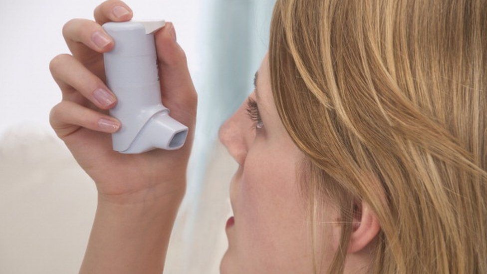 A woman using an inhaler
