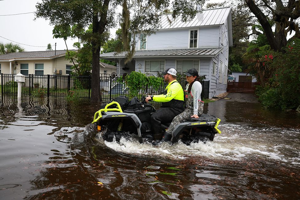 Люди едут на квадроциклах по затопленным улицам, вызванным ураганом Идалия, проходящим мимо берега, 30 августа 2023 года в Тарпон-Спрингс, Флорида