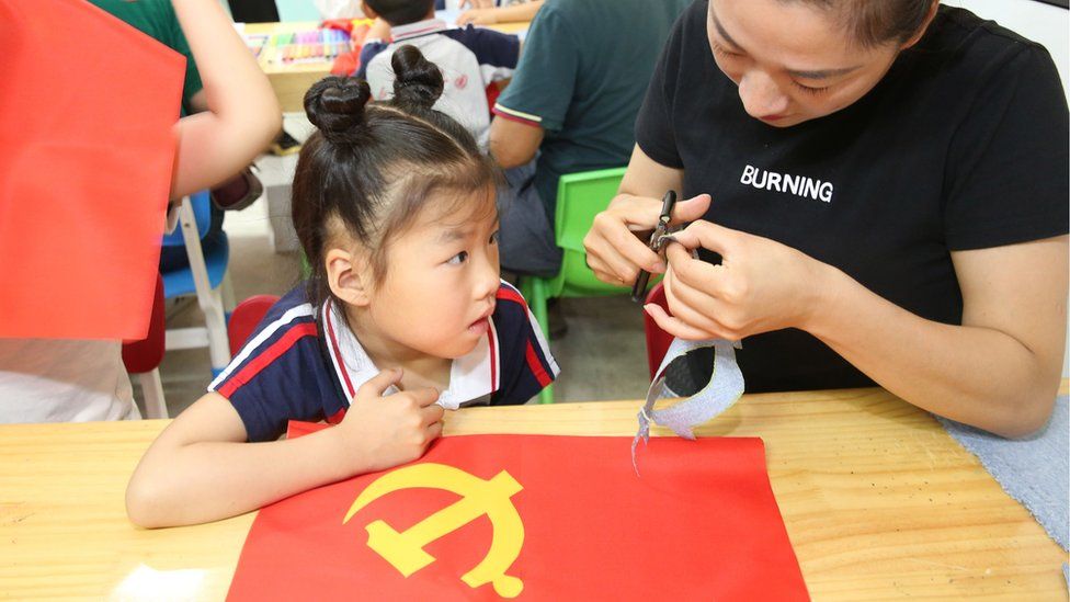 A schoolgirl makes a flag of the Communist Party of China
