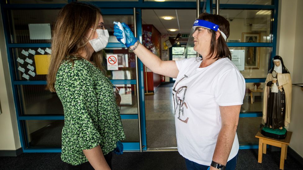 A teacher has her temperature checked by an assistant teacher in Belfast, 24 August 2020.