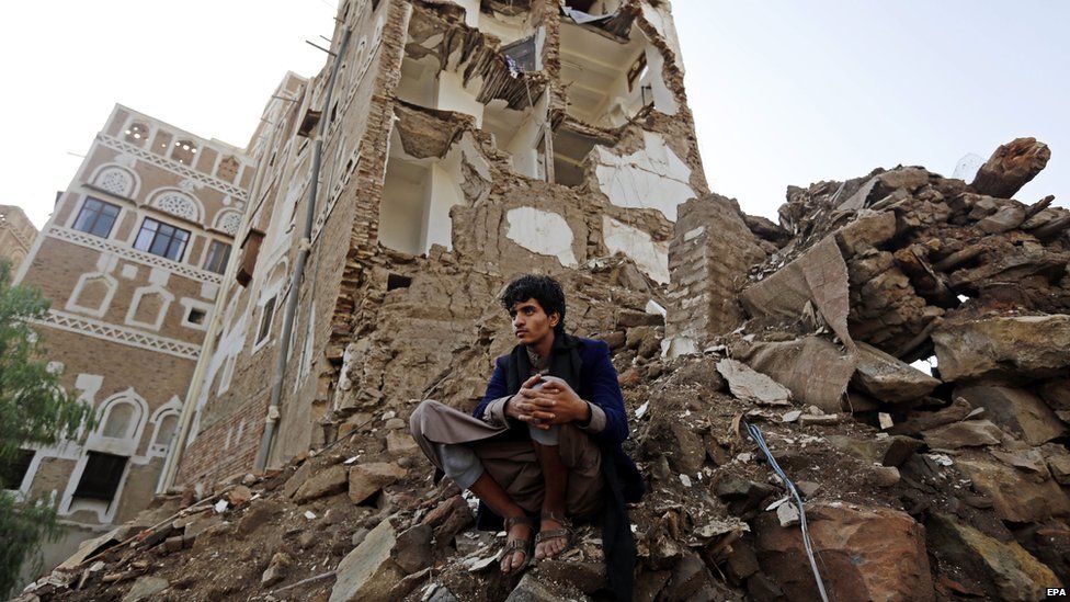 A Yemeni man looks on as a team of the International Committee of the Red Cross (ICRC) delegates inspects the scene of a Saudi-led coalition air strike in Sanaa's Old City (9 August 2015)