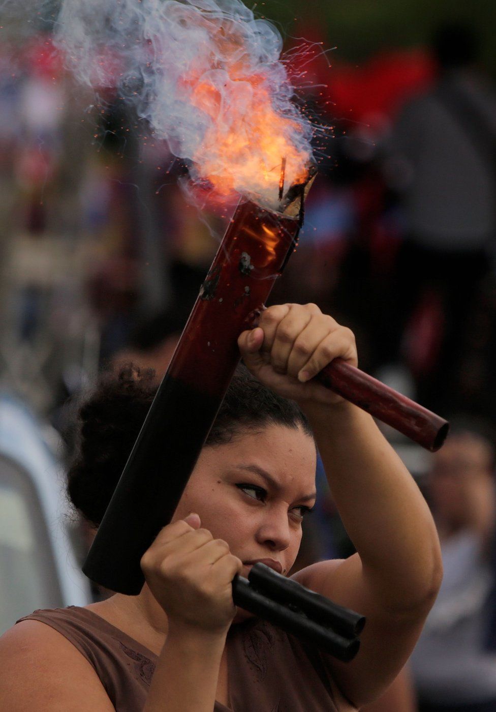 A woman fires a home-made mortar vertically into the air during a pro-government rally