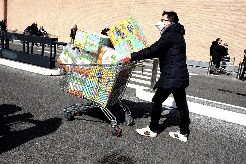 A man with a shopping trolley piled high with food