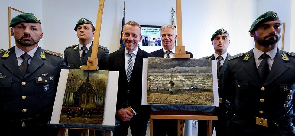 Unsmiling officers flank a beaming Dutch museum curator as the paintings "Congregation Leaving The Reformed Church of Neunen" and "The Beach At Scheveningen During A Storm" by Vincent Van Gogh are displayed during an Italian investigators' press conference in Naples (30 September 2016)