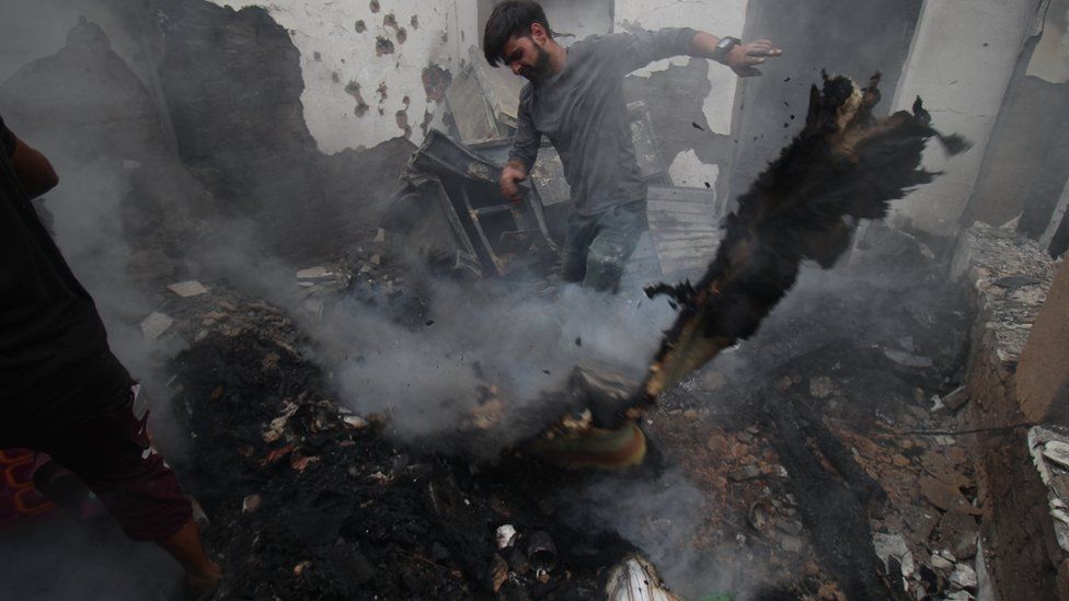 Мужчина убирает обломки дома, пострадавшего в перестрелке между боевиками и индийскими войсками