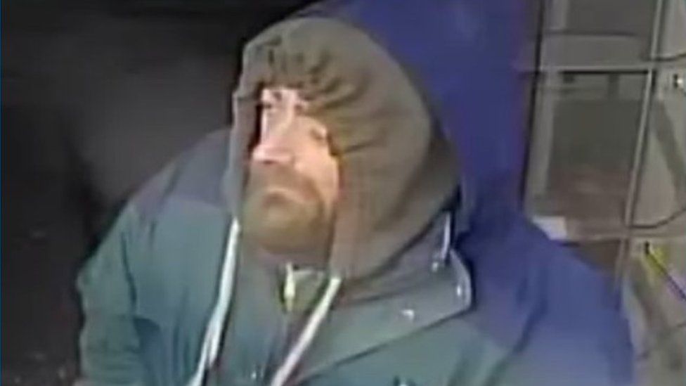 CCTV of a man with a full beard who is wearing a coat with the hood pulled up