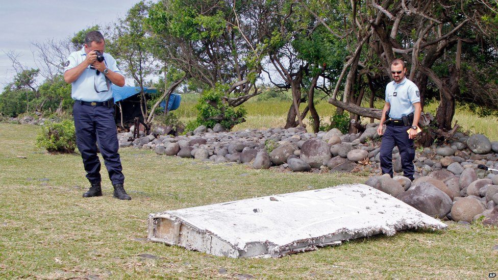 In this photo dated Wednesday, July 29, 2015, French police officers look over a piece of debris from a plane in Saint-Andre, Reunion Island.
