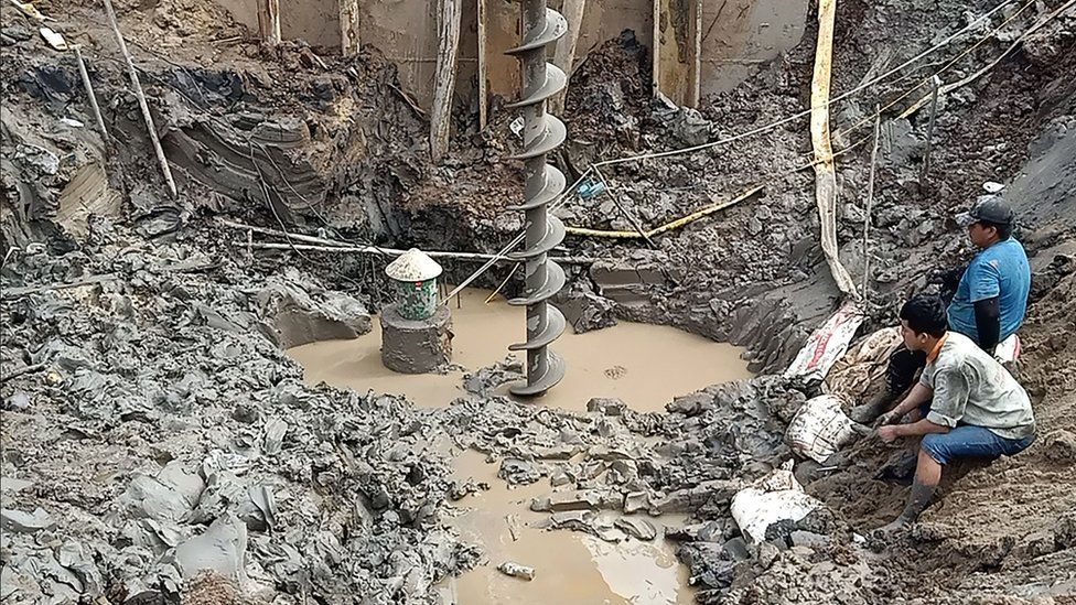 Rescuers gather at the site of where a 10-year-old boy is thought to be trapped in a 35-metre deep shaft at a bridge construction area in Vietnam's Dong Thap province on January 2, 2023.