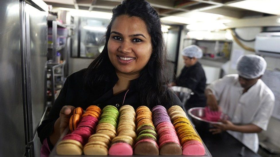 In this photograph taken on February 20, 2015, Indian pastry chef Pooja Dhingra poses holding a tray of macaroons at the Le15 - Patisserie bakery in Mumbai.