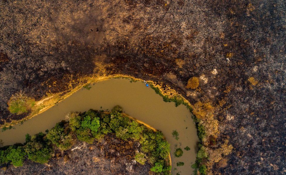 A drone shows scorched earth next to a river