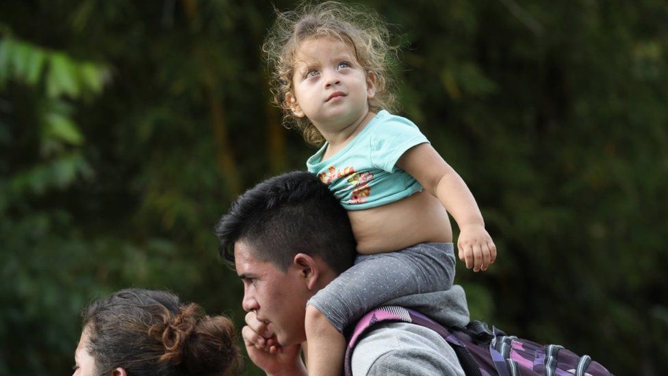 A migrant child on a young man's shoulders