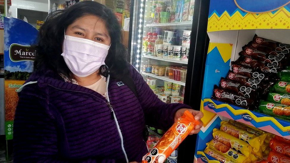 Роза Кайсо Фокко держит пачку печенья с предупреждающей этикеткой в ​​Чили