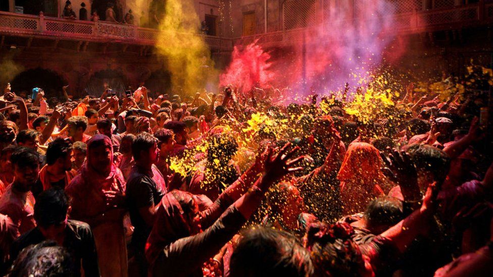 VRINDAVAN, INDIA - 2023/03/05: Hindu devotees pray at Radha Ballav Temple during the holi festival with colorful powders (Gulal). Radha Ballav Temple is one of the oldest and most auspicious temples for Hindus, where Lord Krishna is worshipped during Holi Festival.