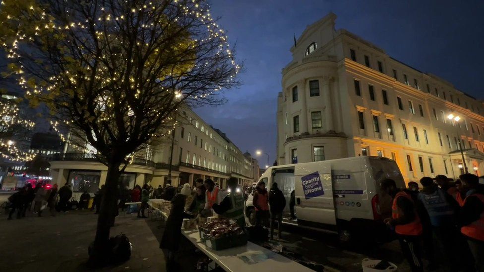 People queue as the charity hands out hot meals on the Strand