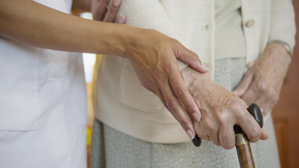 Stock image of a care worker assisting an older person