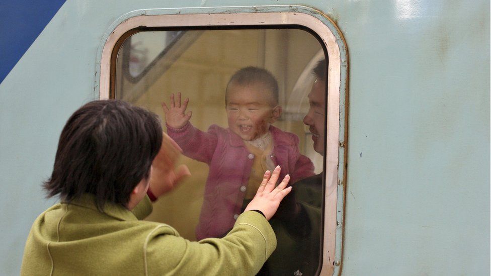 A Chinese baby waves to her mother