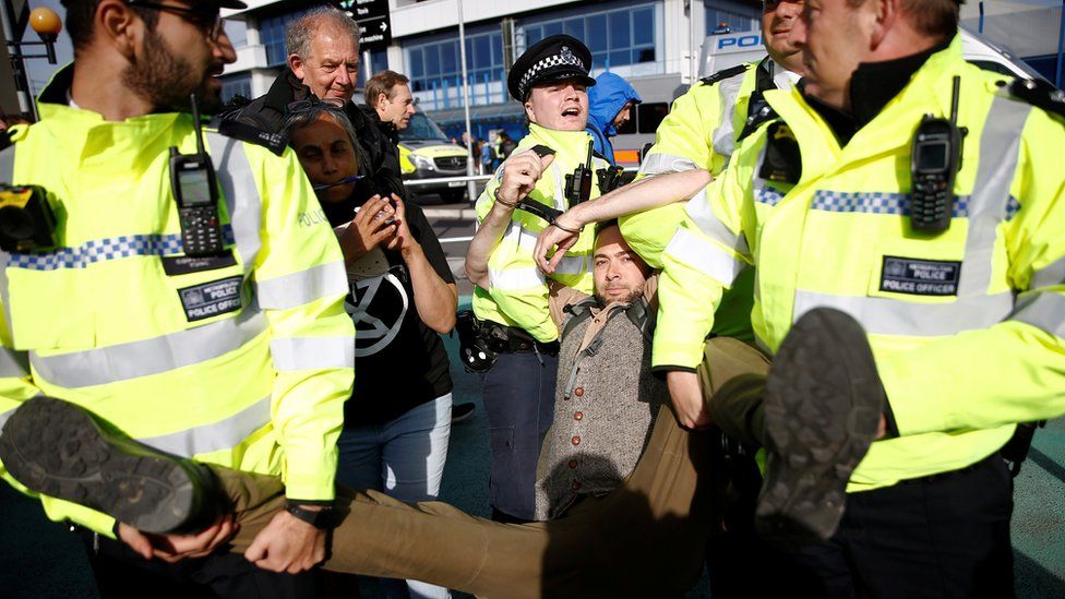A protester is carried away by police during a demonstration at London City Airport