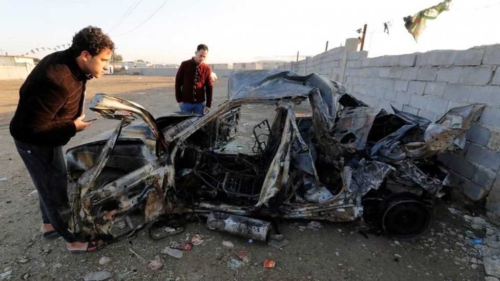 Men look at the wreckage of a burnt car after a suicide bomber detonated a pick-up truck in Sadr City on Wednesday (15 February 2017)