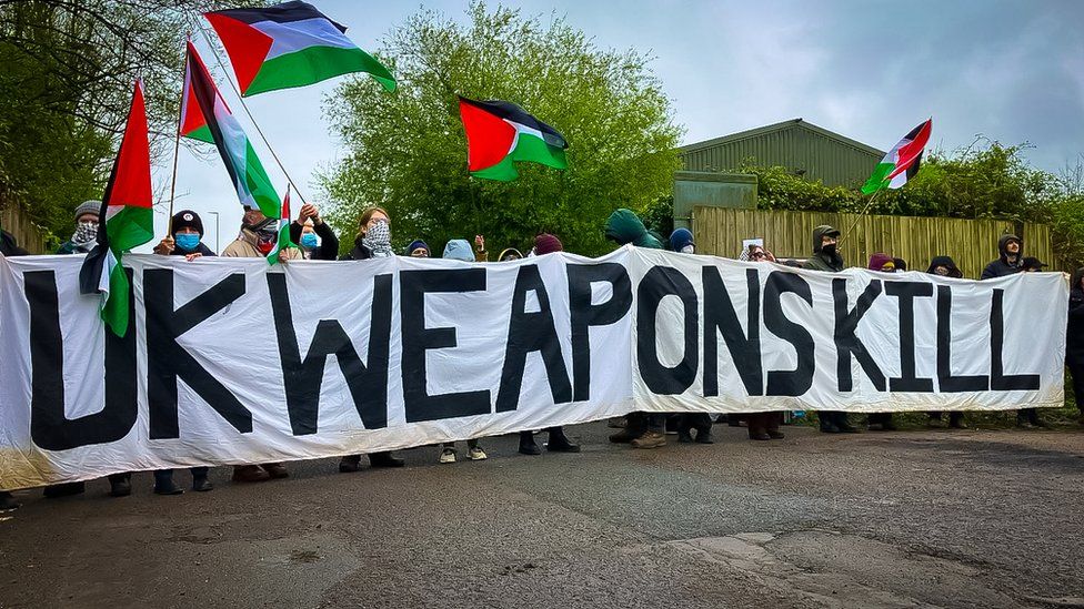 Protesters waving Palestinian flags and holding a banner saying UK weapons kill