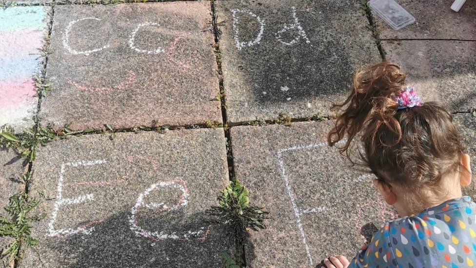 A child drawing letters with chalk in a garden