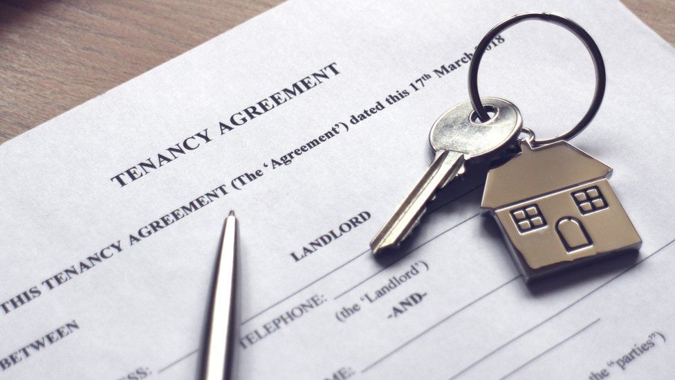 A house key resting on a tenancy agreement contract.