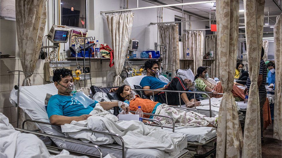 Пациенты, заразившиеся коронавирусом, лежат в кроватях, пока подключены к запасам кислорода в отделении неотложной помощи больницы Covid-19 3 мая 2021 года в Нью-Дели, Индия
