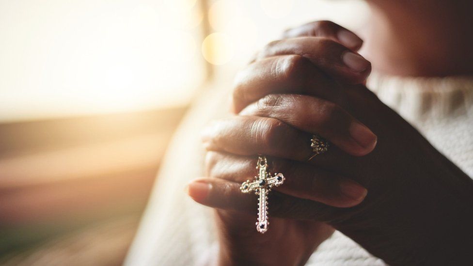 Closeup shot of an unrecognizable woman holding a rosary while praying