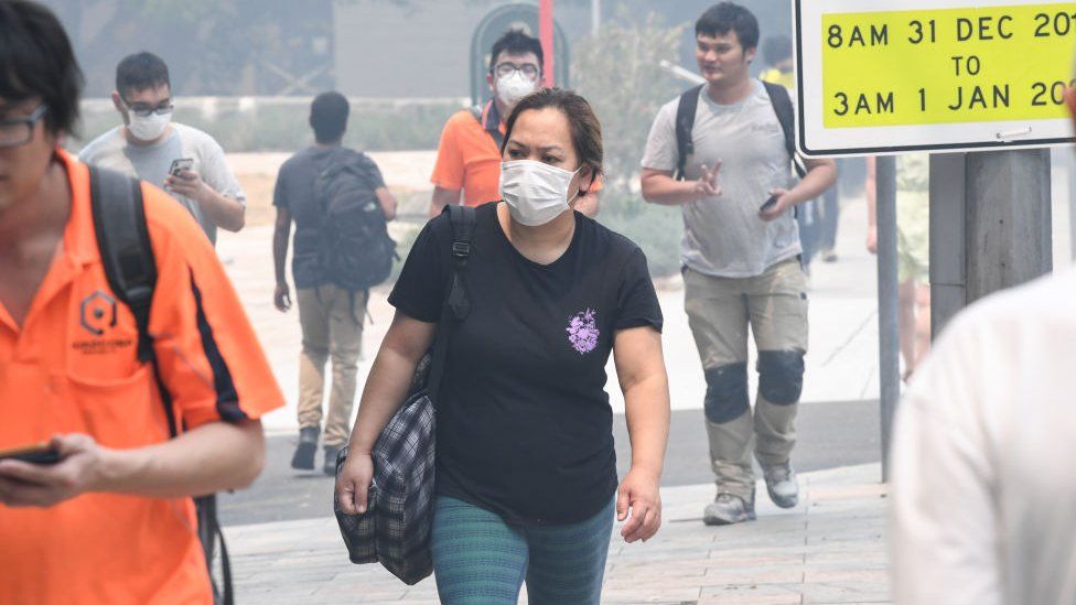 People wear face masks while walking through Sydney