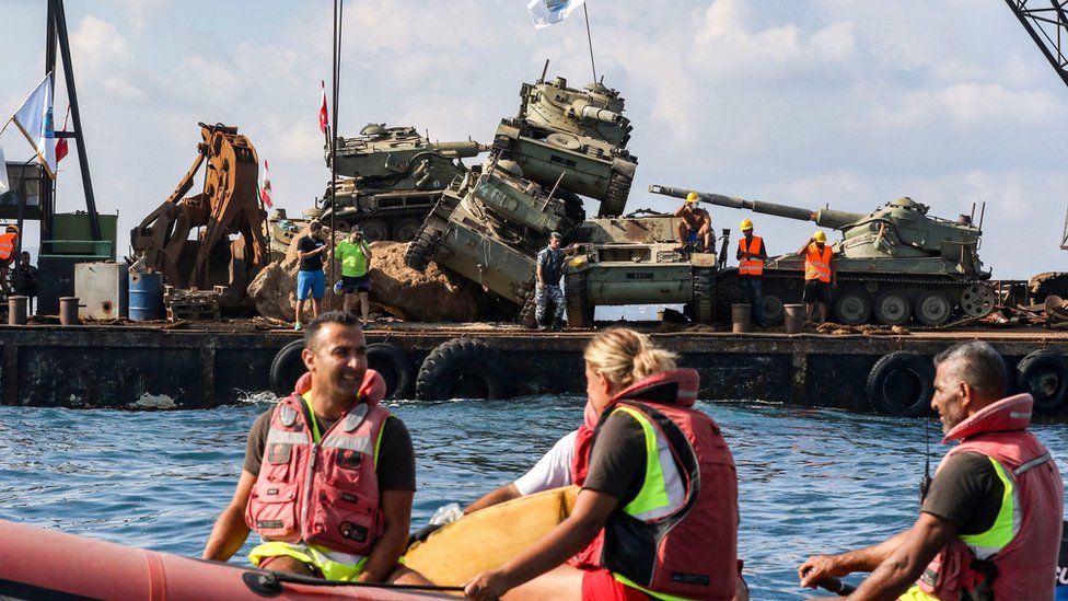 People float in a boat look at the piles of tanks
