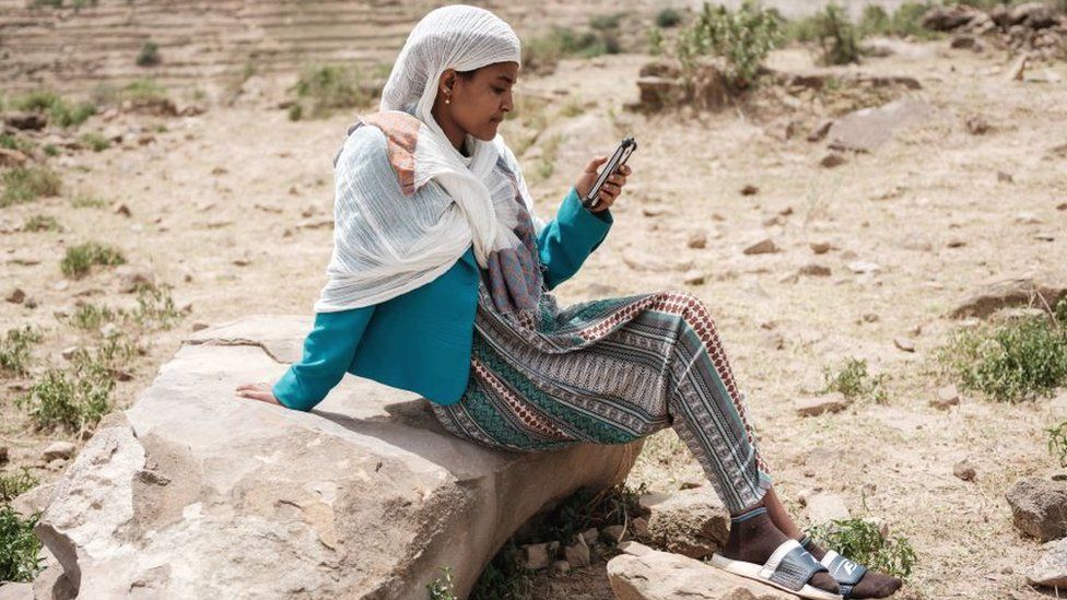 Женщина смотрит на мобильный телефон в районе Тыграй, Эфиопия, июнь 2021 г.