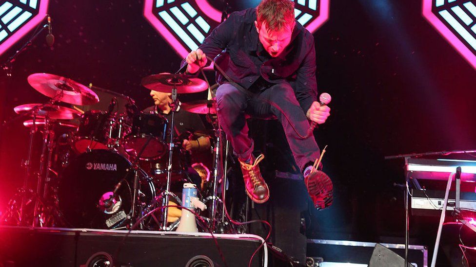 Damon Albarn of Blur jumps up on stage during a concert