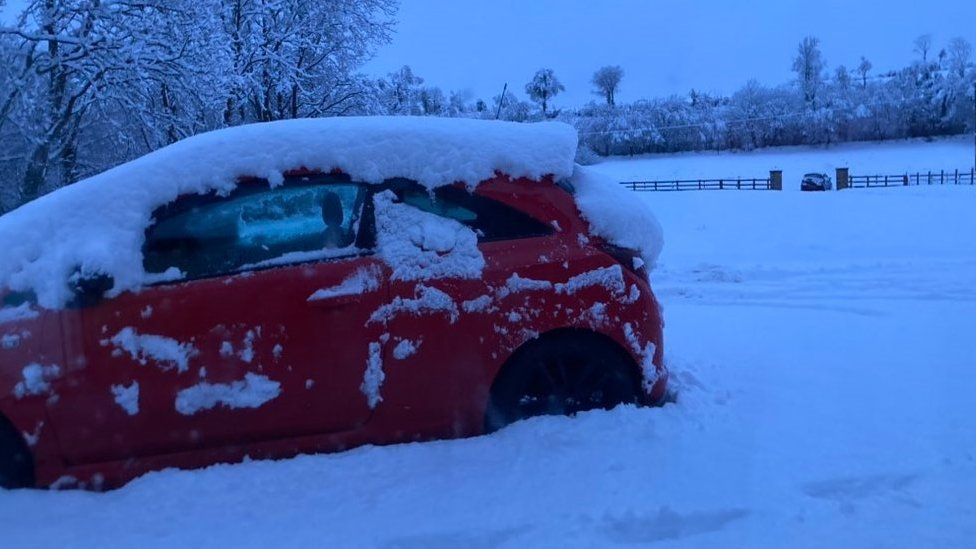 A car stuck in heavy snowfall in the countryside
