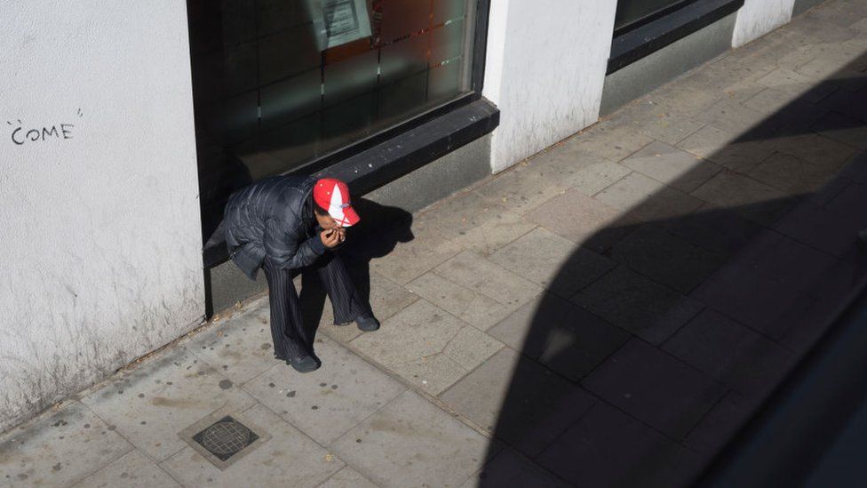 A person wearing an England cap looks down at the ground in Camberwell