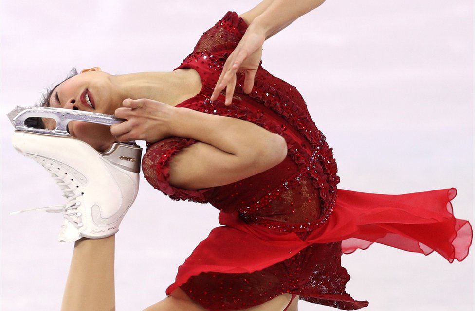 Kaori Sakamoto holds her ice skate up to her head whilst competing