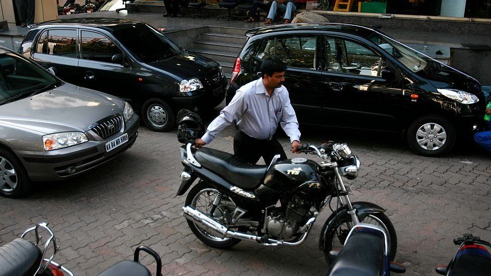 A man pushes his motorbike out of a car dealership, on April 14, 2008 in Bangalore, India.