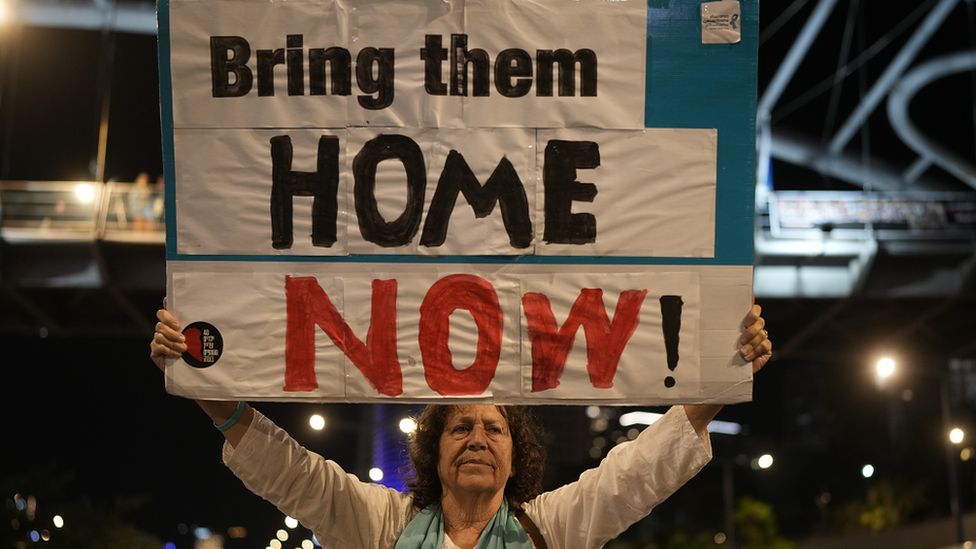 A woman holds a sign in Tel Aviv, Israel demanding the hostages are brought home (21 November 2023)