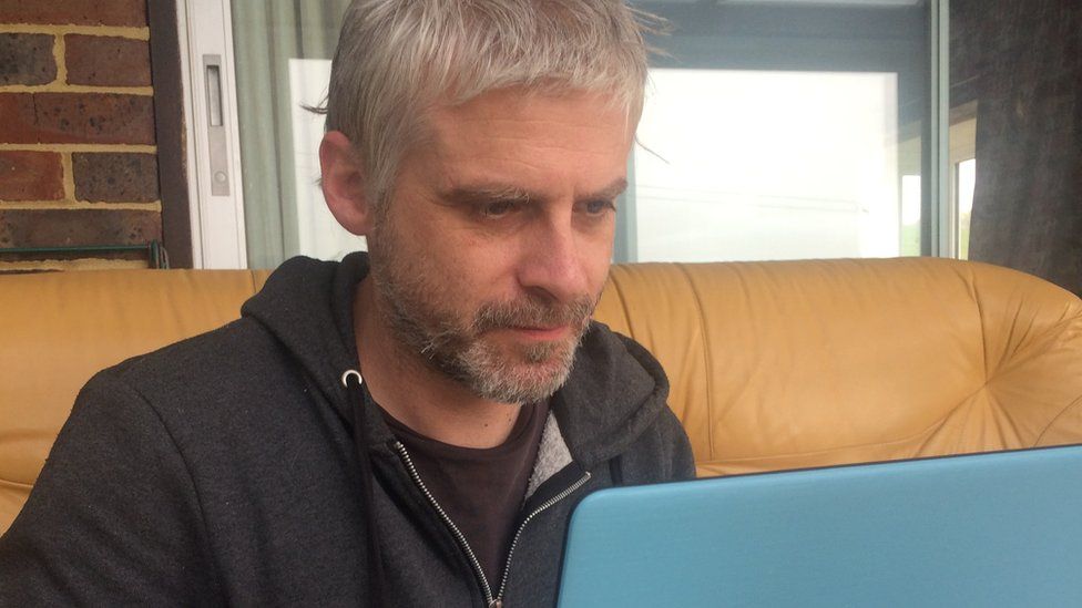 Iain Taylor, who writes fake reviews, sits at his laptop