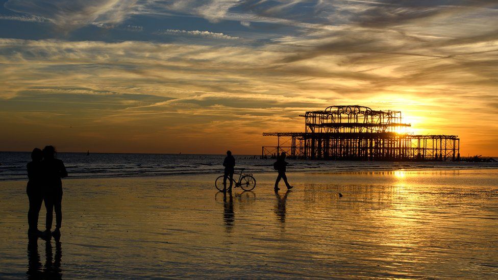 People on Brighton beach near the West Pier at sunset in September 2015