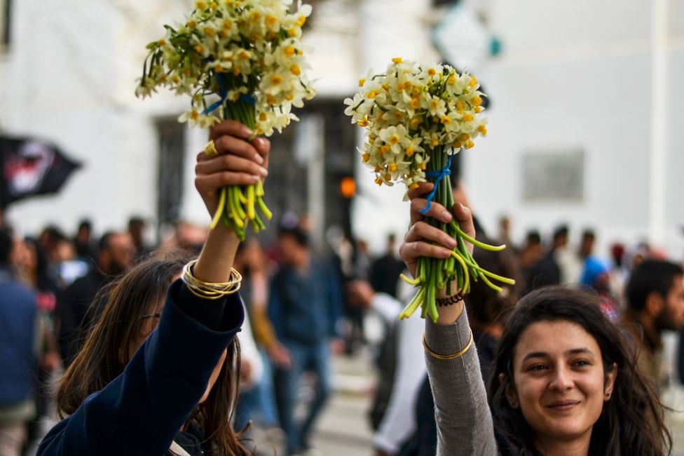 Anti-racism protesters hold up flowers in Tunis, Tunisia - Saturday 25 February 2023
