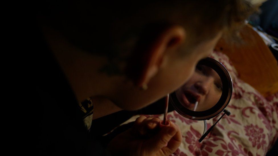 Georgie in a mirror applying makeup