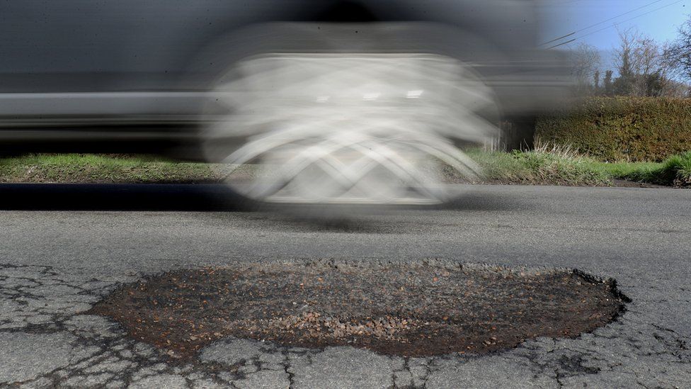 Car driving past a pothole